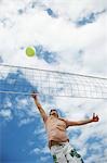 Teenage boy (16-17) playing volleyball, low angle view