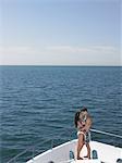 Young couple embracing on bow of yacht, face to face, side view