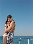 Young couple embracing on yacht, smiling, side view