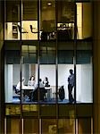 Group of business people at meeting in office, view from building exterior