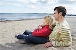Couple assis sur la plage, embrassant