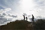 Silhouette de parents et de sa fille (5-6) marcher sur les dunes de sable