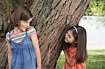 Zwei Mädchen (7-9) spielen Versteckspiel von tree