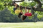 Two girls (7-9) hanging upside down in tree