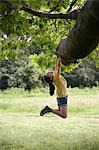 Girl (7-9) hanging from tree