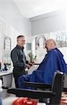 Barber and man in barbers shop, smiling