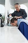 Barber washing mans head in barber shop