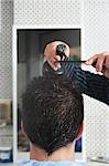 Barber spraying mans hair in barber shop, close-up