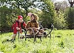 Young boy (7-9) in pirate costume pushing boy (5-6) in cart in jaguar costume, smiling