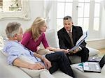 Senior couple sitting on sofa with financial advisor, elevated view