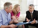 Senior couple sitting on sofa with financial advisor