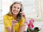 Frau hält Kreditkarte unter Telefon im Wohnzimmer, Porträt