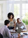 Young African American couple discussing home finances with financial advisor at dining room table