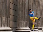 Soccer player kicking ball, standing between columns