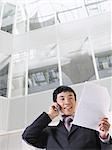 Homme d'affaires à l'aide de téléphone portable dans l'atrium de l'édifice à bureaux, vue d'angle faible