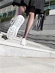 Business woman wearing running shoes, walking up steps, low section, low angle view, back view