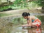 Jeune femme accroupie dans le lac, vue latérale