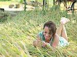Young woman lying on meadow, playing with grass, smiling