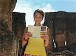 Young woman reading guide book, ancient ruins in background