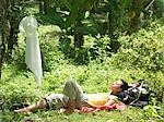 Young woman lying in tropical forest, sunbathing