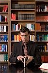 Man wearing suit opening book at desk in library