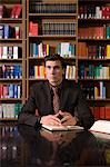 Pensive man wearing suit with book at desk in library