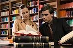 Young man and woman studying at desk in library