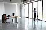 Man looking out of window in empty office building