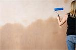 Mur peinture femme avec rouleau à peinture, vue arrière