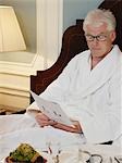 Mann sitzt auf dem Bett Dokument lesen