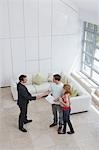 Real estate agent with couple in new home, man shaking hand, elevated view