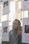 Couple regardant par la fenêtre aux agents immobiliers