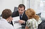 Couple observing brochure with real estate agent in office