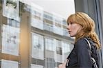 Woman looking in window outside estate agents