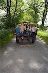 Parents with three children (5-9) sitting on trailer on country lane