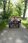 Parents with three children (5-9) sitting on trailer on country lane