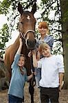Mutter und Kinder (5-6, 7-9) mit Pferd im Freien, Porträt