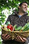 Man holding fruit and vegetable basket, outdoors