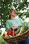 Woman holding fruit and vegetable basket, outdoors