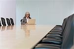 Business woman using laptop in board room