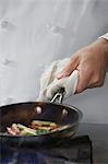 Chef cooking food in frying pan, close-up