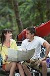 Couple with map sitting on car