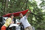 Couple with map on car bonnet in forest, man pointing