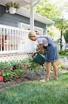 Girl (7-9) watering flowers at house back yard