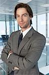 Business man with arms crossed, in office building, portrait