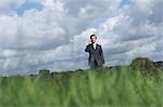 Business man talking on mobile phone in field, selective focus