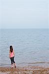 Jeune femme debout sur la plage, vue arrière