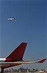 Close-up of airplane's tail fin, flying plane in background