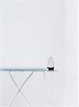 Iron on ironing board against white wall