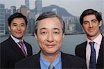 Portrait of three business men, office buildings in background